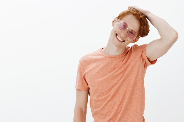 Foto gratuita hombre guapo pelirrojo despreocupado disfrutando del verano, con gafas de sol y sonriendo