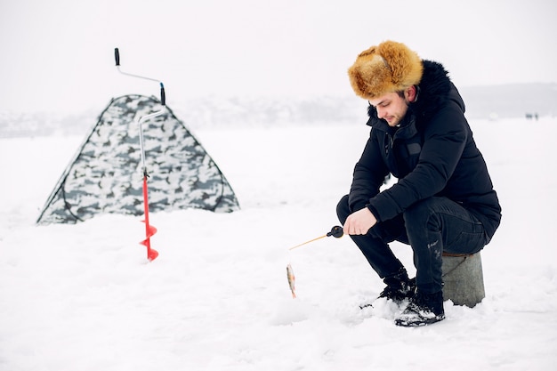 Hombre guapo en una pesca de invierno