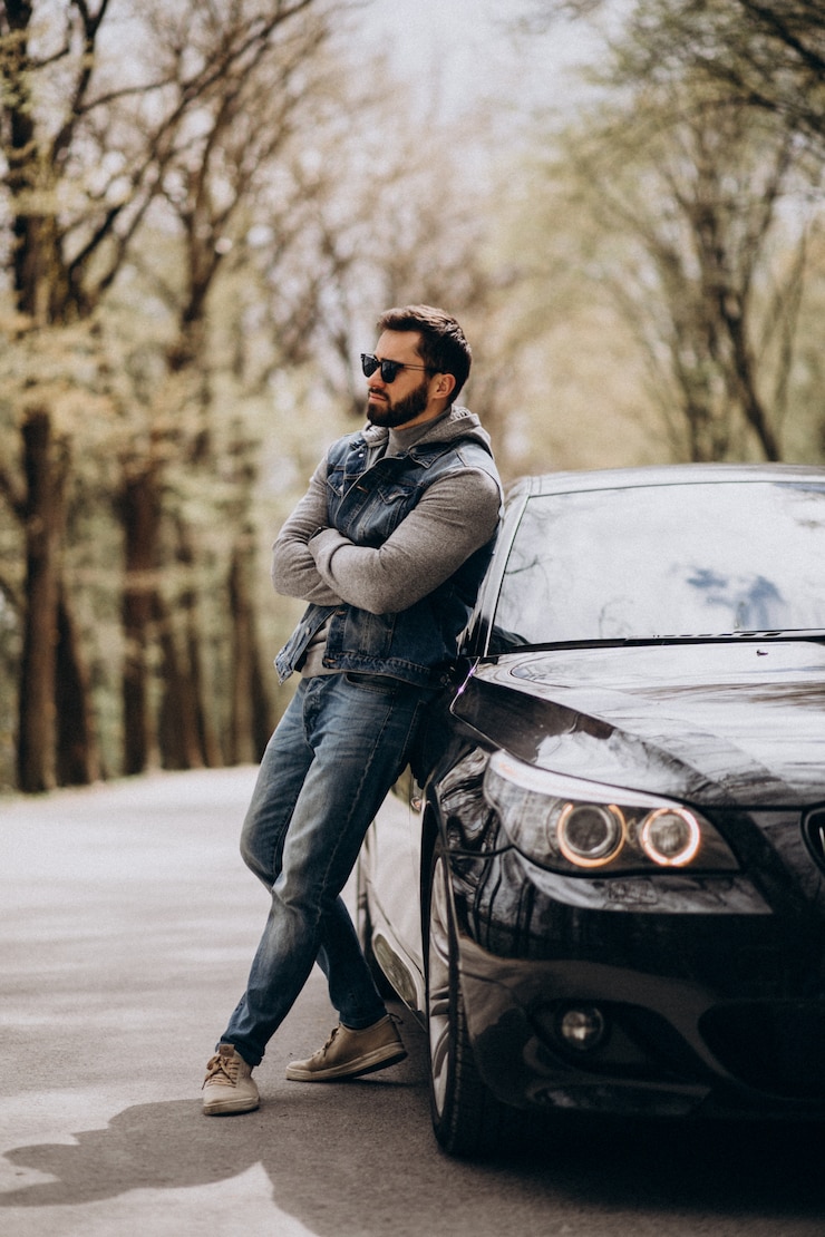 Foto gratuito hombre guapo de pie junto al coche en el parque