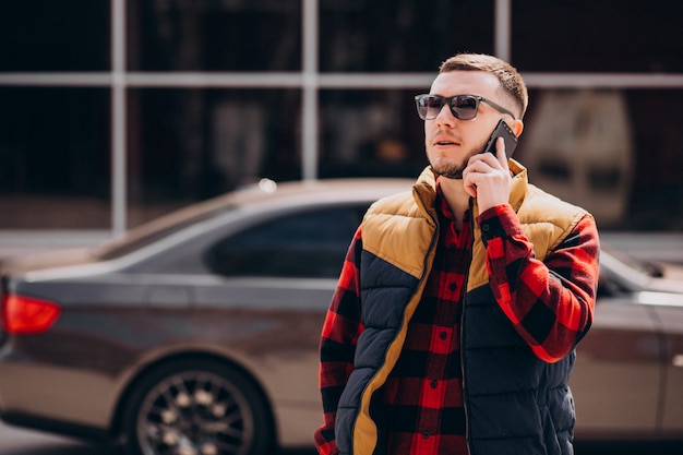 Hombre guapo de pie junto al coche