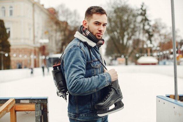 Hombre guapo en una pista de hielo con skate