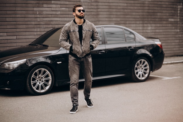 Hombre guapo posando junto al coche en la calle