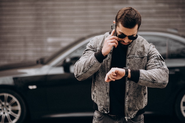 Hombre guapo posando junto al coche en la calle