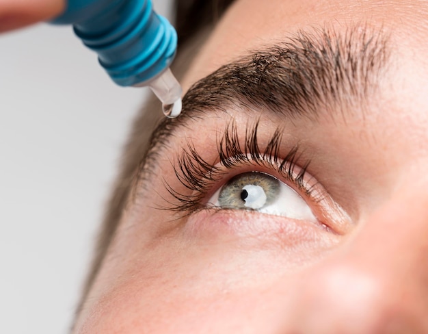 Hombre guapo con primer plano de gotas para los ojos