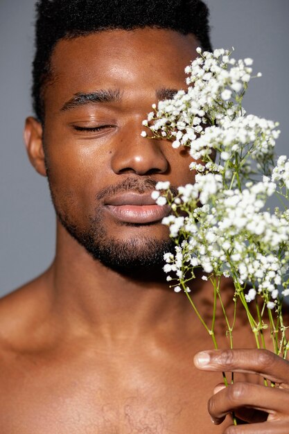 Hombre guapo de primer plano posando con flores