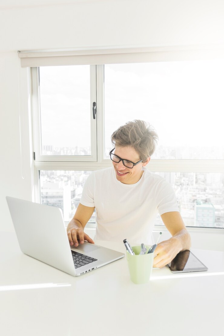Foto gratuito hombre guapo que trabaja en la computadora portátil en casa