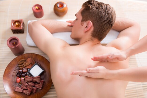 Hombre guapo relajado y disfrutando de un masaje de espalda de tejido profundo en el salón de spa.