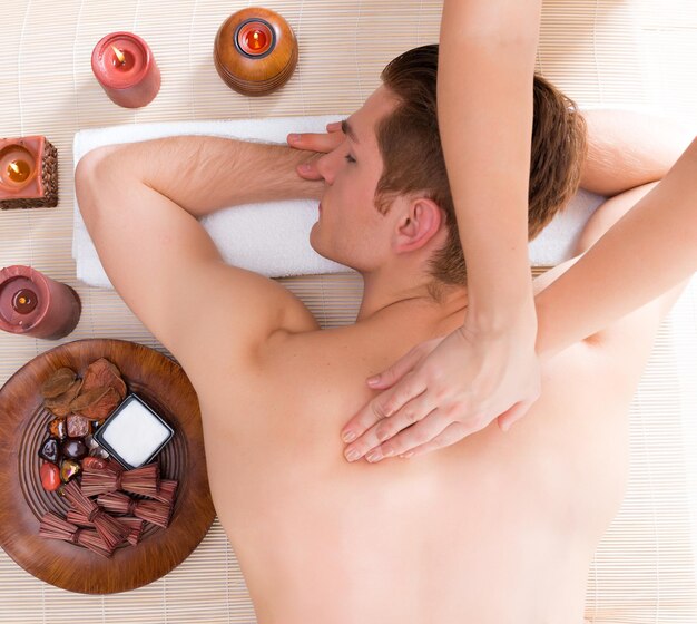 Hombre guapo relajado y disfrutando de un masaje de espalda de tejido profundo en el salón de spa.