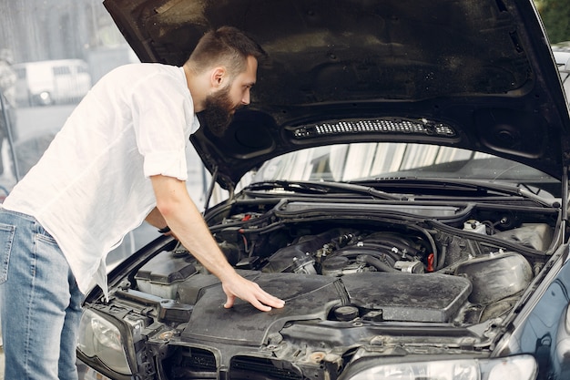 Foto gratuita hombre guapo revisa el motor de su auto