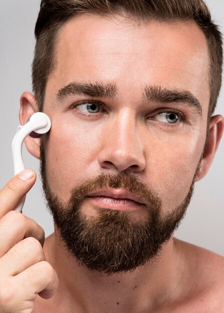 Hombre guapo con un rodillo para limpiar su cara