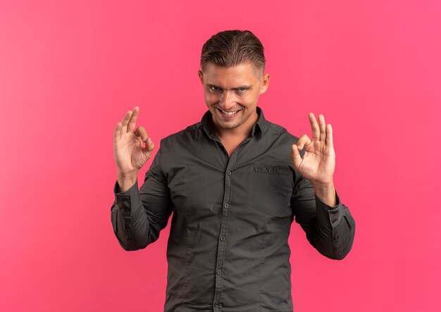 Hombre guapo rubio sonriente confiado joven gestos ok signo de mano aislado en el espacio rosa con espacio de copia