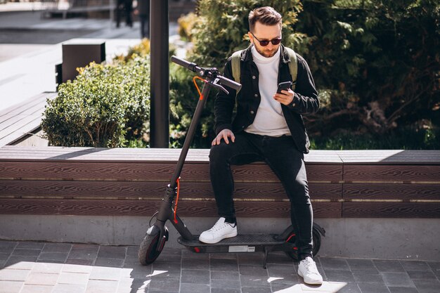 Hombre guapo en scooter de compras en línea por teléfono