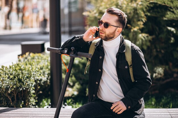 Hombre guapo en scooter de compras en línea por teléfono