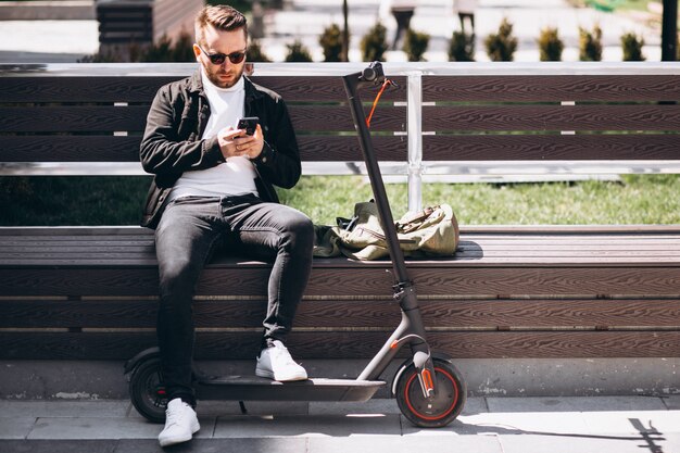 Hombre guapo en scooter de compras en línea por teléfono