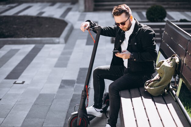 Hombre guapo en scooter de compras en línea por teléfono