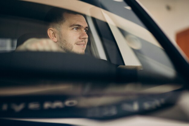 Hombre guapo sentado en el coche y probarlo