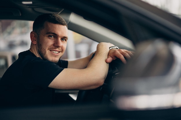 Hombre guapo sentado en el coche y probarlo