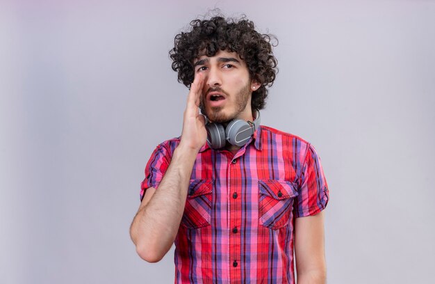 Un hombre guapo serio con cabello rizado en camisa a cuadros en auriculares llamando a alguien