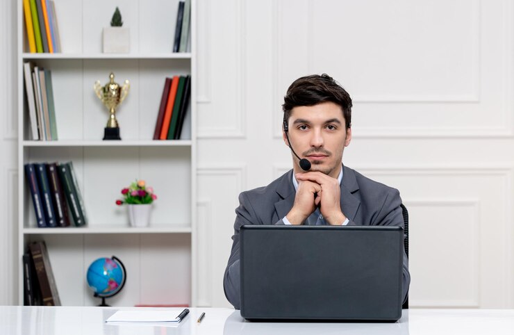 Foto gratuito hombre guapo de servicio al cliente en traje gris con computadora y auriculares