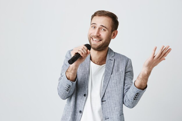 Hombre guapo sonriente cantando karaoke con micrófono