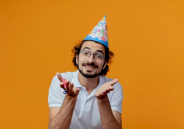 Foto gratuita hombre guapo sonriente con gafas y gorro de cumpleaños sosteniendo las manos aisladas en la pared naranja