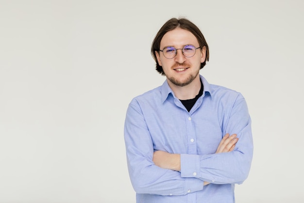 Hombre guapo sonriente de pie con los brazos cruzados aislado sobre fondo gris