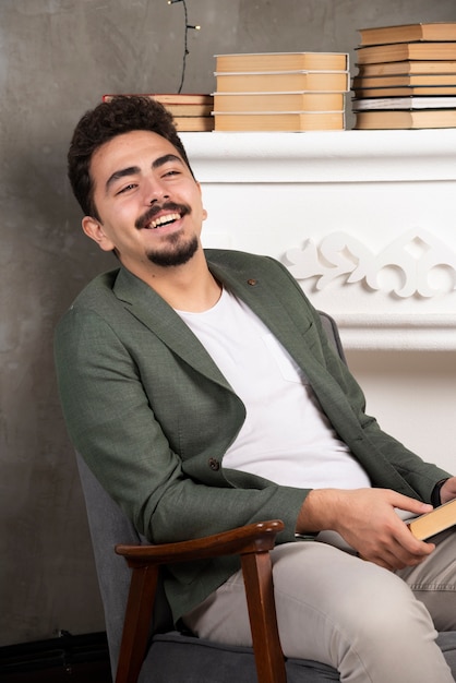 Hombre guapo sonriente sosteniendo su libro en la mano.