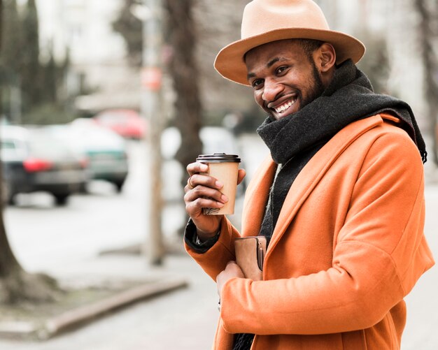 Hombre guapo sonriente sosteniendo una taza de café de papel