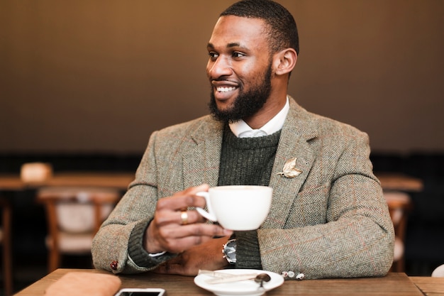 Hombre guapo sonriente sosteniendo una taza con café