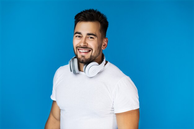 Hombre guapo sonriente sostiene sus auriculares en el cuello