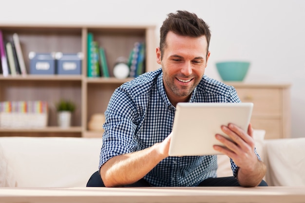 Hombre guapo sonriente con tableta digital en casa