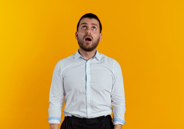 Hombre guapo sorprendido busca aislado en la pared naranja