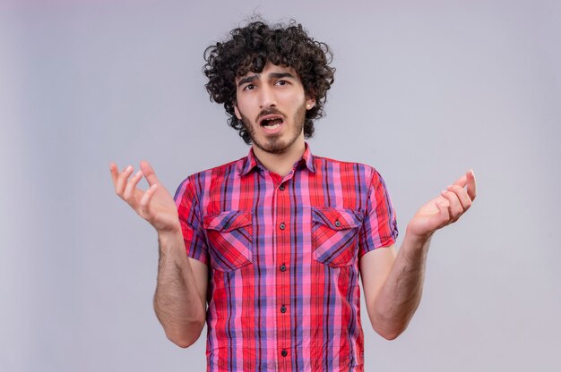 Un hombre guapo sorprendido con el pelo rizado en camisa a cuadros levantando las manos