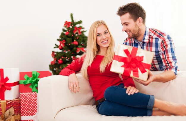 Hombre guapo sorprendiendo a su novia con regalo de Navidad