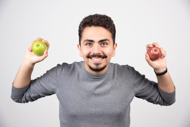 Hombre guapo sosteniendo manzanas en gris.