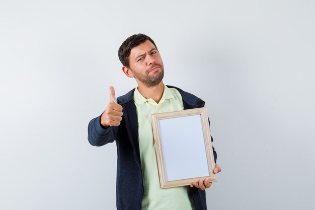 Hombre guapo sosteniendo un marco de fotos con un traje casual