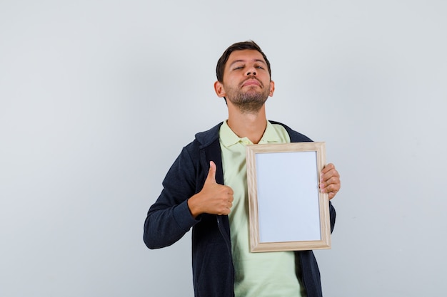 Hombre guapo sosteniendo un marco de fotos con un traje casual