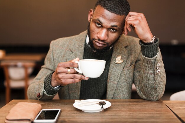 Hombre guapo sosteniendo una taza con café mientras mira hacia arriba