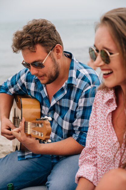 Hombre guapo tocando la guitarra y cantando una canción para sus mejores amigos