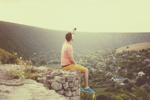 Hombre guapo tomando fotos de él mismo con cámara de acción. Filtro de instagram vintage retro