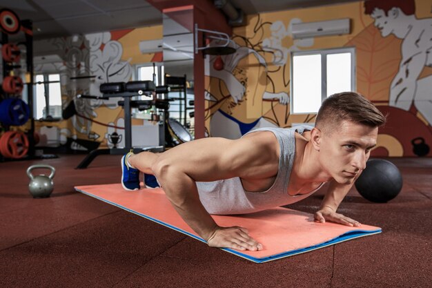 Hombre guapo trabajando flexiones en el gimnasio. Ejercicios deportivos