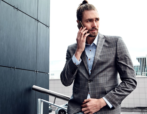 Hombre guapo en traje a cuadros gris hablando con teléfono inteligente