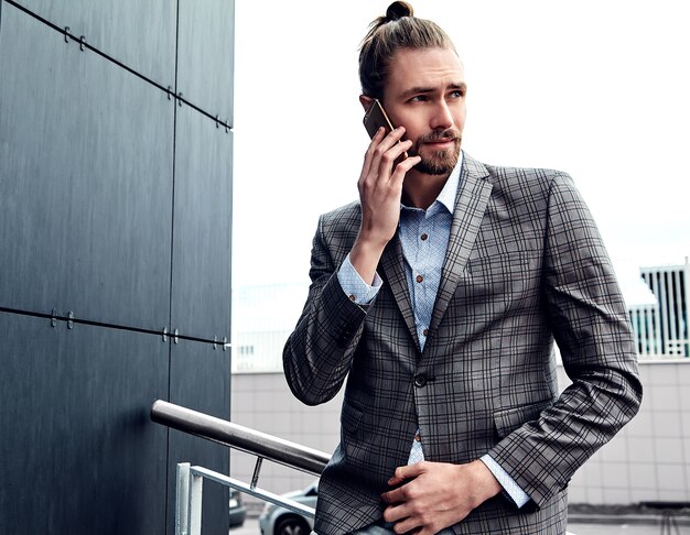 Hombre guapo en traje a cuadros gris hablando con teléfono inteligente