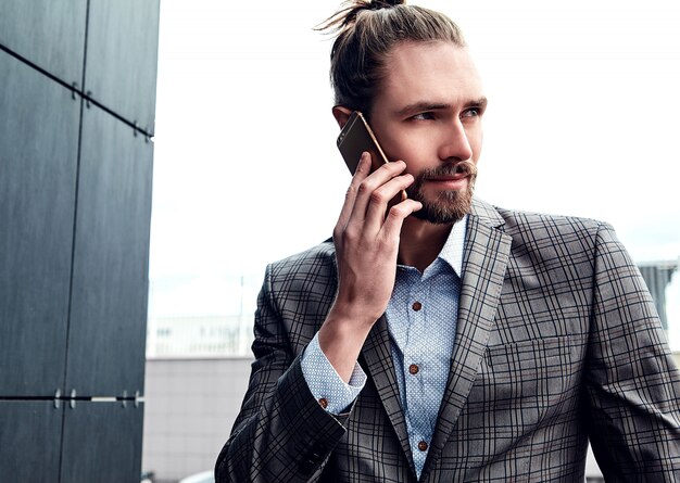 Hombre guapo en traje a cuadros gris hablando con teléfono inteligente