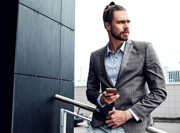 Hombre guapo en traje a cuadros gris con smartphone