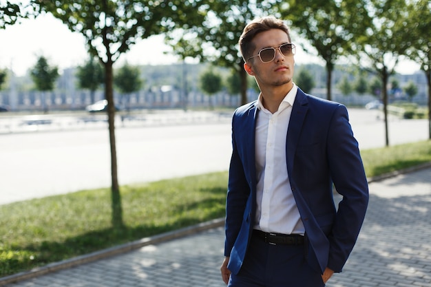 Hombre guapo en un traje de negocios camina por la calle en un día soleado