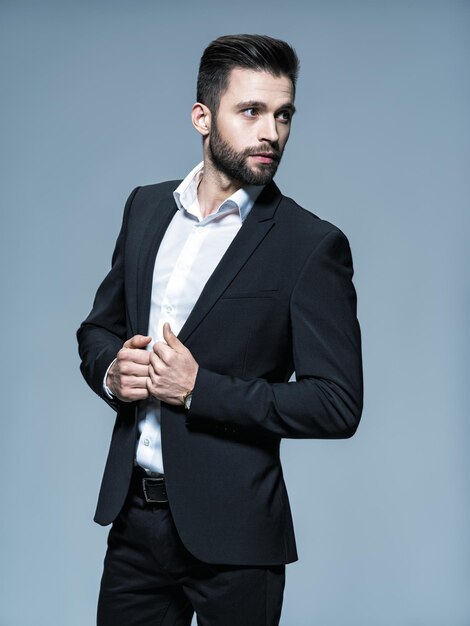 Hombre guapo en traje negro con camisa blanca - posando Chico atractivo con peinado de moda. Hombre confiado con barba corta. Chico adulto con cabello castaño. Retrato completo.