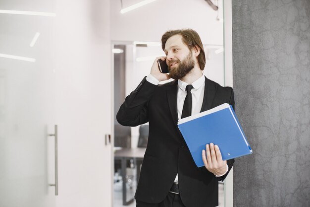 Hombre guapo con traje negro. Hombre de negocios con teléfono móvil.