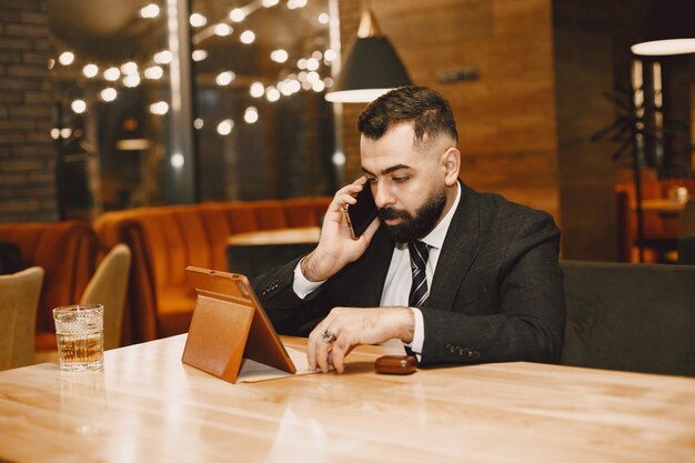 Hombre guapo con traje negro, trabajando en un café