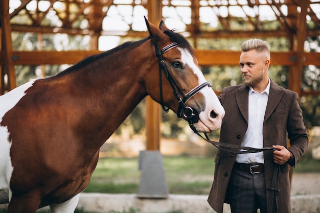 Hombre guapo en traje en el rancho a caballo